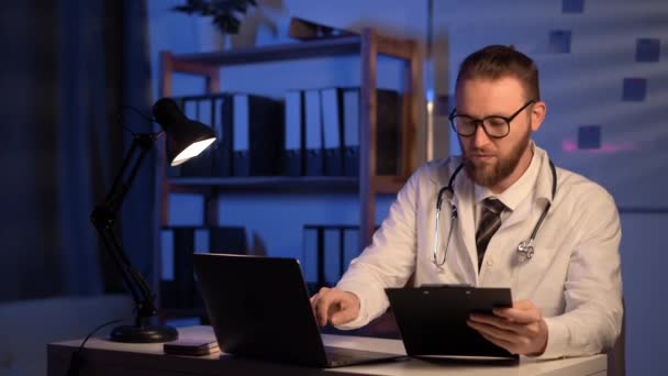 Doctor Typing Laptop Keyboard Information Clipboard Patient List While Working — Vídeo de stock