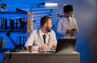 Doctors working night shift in hospital, colleagues therapists at workplace discussing diagnoses and tests of patients. Copy space