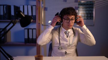 Happy excited doctor listening to music during shift in hospital at the night. Copy space