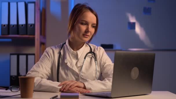 Νεαρή Γυναίκα Γιατρός Στηθοσκόπιο Χρησιμοποιώντας Φορητό Υπολογιστή Μιλώντας Ακούγοντας Τηλεδιάσκεψη — Αρχείο Βίντεο