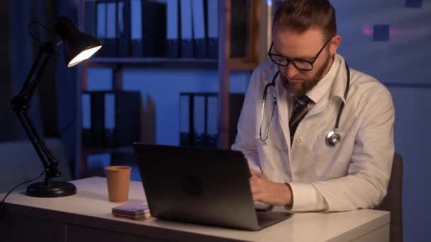 Serious Male Doctor Using Laptop Writing Notes Medical Journal Sitting — Stockvideo