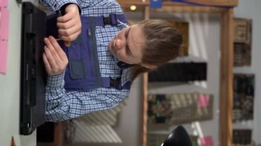 Dizüstü bilgisayarın tornavidayla sökülmesi. Elektronik tamir atölyesindeki bozuk bilgisayarı tamir eden kadın mühendis. Bilgisayar tamirhanesi konsepti. Dikey video