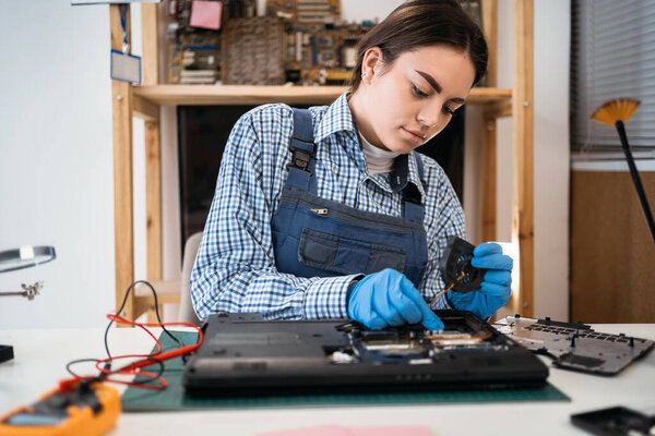 Service woman holds a laptop cooling fan for a repair and cleaning. Technician fix and install to laptop computer. Copy space