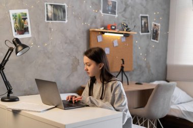 Young asian female student using a laptop pc. student e learning distance training course study work at home office, looking at a laptop. Copy space