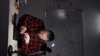 Service center for the repair of digital gadgets. The worker sits at the table with a screwdriver unscrews the lid of the laptop. copy space. Vertical video