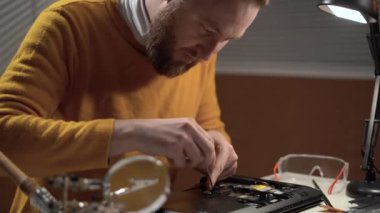 Service center for the repair of digital gadgets. worker with a screwdriver unscrew the screws in the laptop. The concept of upgrade or service pc copy space.