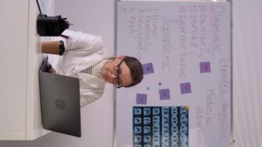 Focused doctor in hospital office working on laptop. Copy space. Vertical video