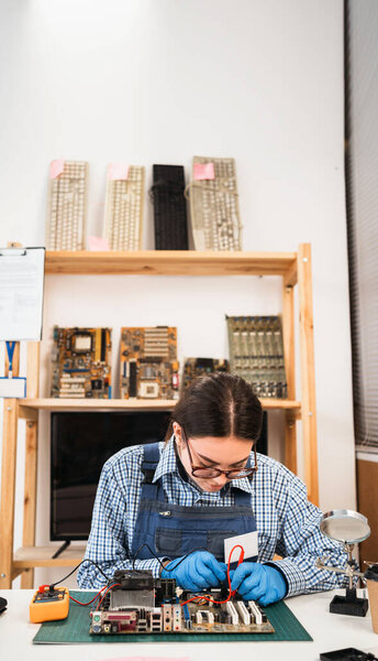 Computer master checks the electronic motherboard and performs electrical measurements. Electronics repair service. Multimeter measuring instrument. Copy space