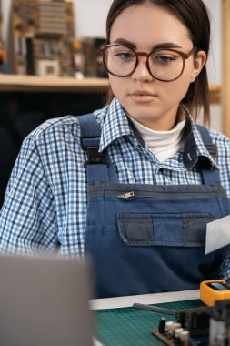Portrait of young female technician smiling while fixing computer hardware. Copy space