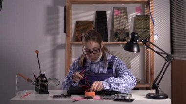 Kadın teknisyen, hasarlı dizüstü bilgisayarı çoklu metre ile kontrol ediyor. Bilgisayar onarımı ve yükseltme kavramı