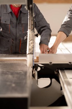 Carpenters working with sliding panel saw and sawing fibreboard at furniture factory workshop. woodworking industry concept. Close up