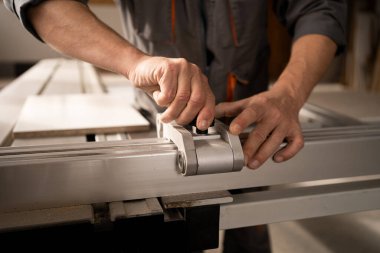 Man working on automatic woodworking machine in furniture factory. Close up