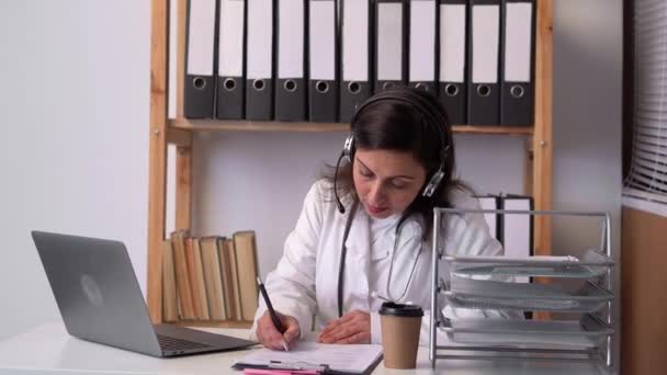 Dokter Zit Aan Balie Van Haar Kantoor Met Headset Laptop — Stockvideo