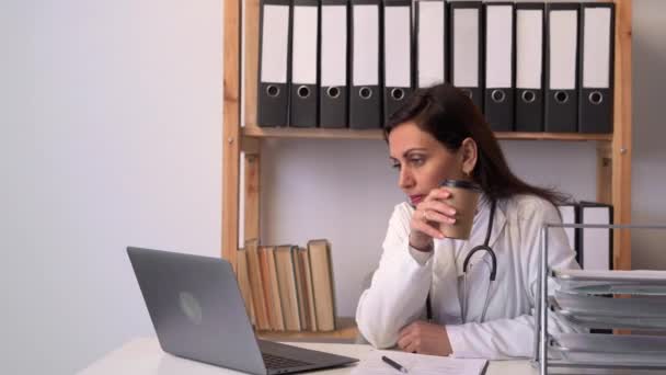 Женщина Врач Работает Офисе Пьет Кофе Объясняя Пациенту Лечение Через — стоковое видео
