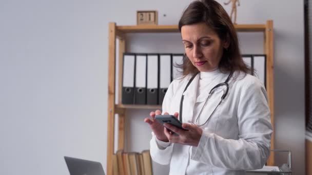 相談に現代の技術アプリを使用して携帯電話と女性医師の肖像画 遠隔医療オンラインサービスの概念です コピースペース — ストック動画