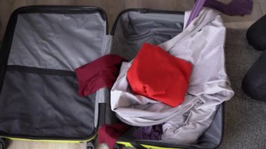 Traveler packing a suitcase for a trip at home throws things and clothes, top view. Woman packing suitcase at home. Travel concept. Close up