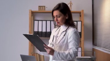 Female medicine doctor writing something on clipboard. Physician ready to examine patient and help. Medical care, insurance, prescription, paper work concept. Copy space
