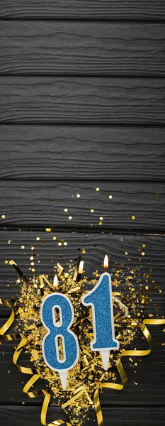 暗い木製の背景に数字81青お祝いのろうそくと金のコンフェッティ 81歳の誕生日カード 記念日と誕生日のコンセプト 縦のバナー スペースのコピー — ストック写真