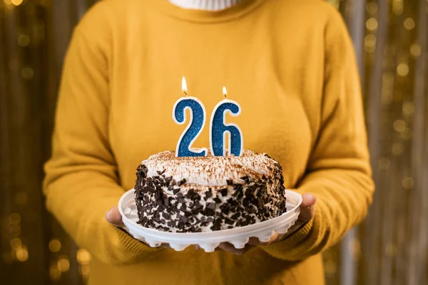 一个女人拿着生日蛋糕 点着26号蜡烛 背对着装饰好的背景 在家里庆祝生日 复制空间 — 图库照片