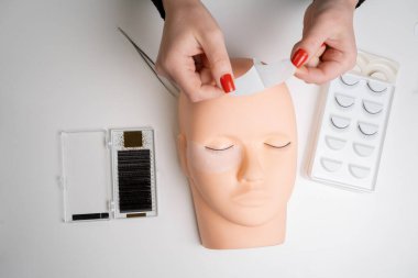 Silikon bir mankenin üzerine kirpik yapmak için temel eğitim. Kirpiklerini uzatmadan önce göz bandıyla çalış. Boşluğu kopyala