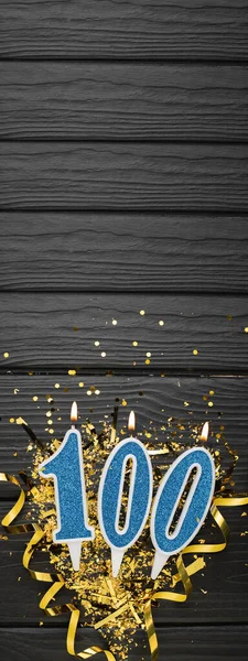 Nummer 100 Blaue Festkerze Und Goldenes Konfetti Auf Dunklem Holzgrund — Stockfoto