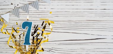 Beyaz ahşap arka planda 7 numaralı mavi kutlama mumu. Mutlu doğum günü mumları. Doğum günü, yıldönümü, önemli tarih, tatil kavramı. Uzayı kopyala Pankart