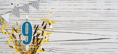 Beyaz ahşap arka planda 9 numaralı mavi kutlama mumu. Mutlu doğum günü mumları. Doğum günü, yıldönümü, önemli tarih, tatil kavramı. Uzayı kopyala Pankart