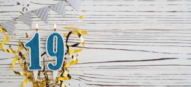 Beyaz ahşap arka planda 19 numaralı mavi kutlama mumu. Mutlu doğum günü mumları. Doğum günü, yıldönümü, önemli tarih, tatil kavramı. Uzayı kopyala Pankart