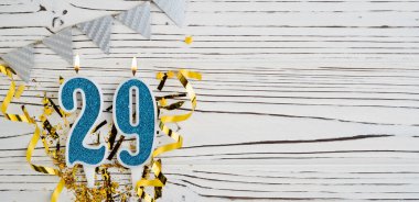 29 numaralı mavi kutlama mumu beyaz ahşap arka planda. Mutlu doğum günü mumları. Doğum günü, yıldönümü, önemli tarih, tatil kavramı. Uzayı kopyala Pankart