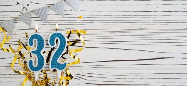 Beyaz ahşap arka planda 32 numaralı mavi kutlama mumu. Mutlu doğum günü mumları. Doğum günü, yıldönümü, önemli tarih, tatil kavramı. Uzayı kopyala Pankart