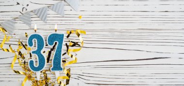 Beyaz ahşap arka planda 37 numaralı mavi kutlama mumu. Mutlu doğum günü mumları. Doğum günü, yıldönümü, önemli tarih, tatil kavramı. Uzayı kopyala Pankart