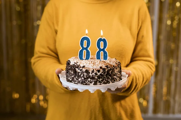 一个女人在庆祝生日的时候拿着一个88号蜡烛的节日蛋糕 生日假期派对的人的概念 特写镜头 — 图库照片