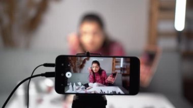 Genç kadın güzellik blogcusu ya da blogcu kameralı akıllı telefonlu kozmetik makyaj videosu çekiyor, sosyal medyada canlı yayında viral videosunu paylaşıyor. Boşluğu kopyala