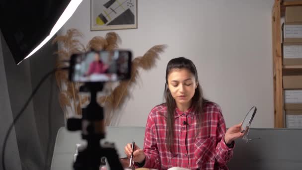 若いヒスパニック系の女性は化粧品を適用しながら彼女のビデオを記録します 装飾化粧品の彼女のブログのためのビデオを作る女性 スペースのコピー — ストック動画