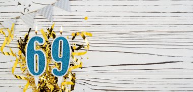 Beyaz ahşap arka planda 69 numaralı mavi kutlama mumu. Mutlu doğum günü mumları. Doğum günü, yıldönümü, önemli tarih, tatil kavramı. Uzayı kopyala Pankart