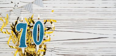 Mavi mum numarası, 70 haneli. 70 yazısıyla birlikte doğum günü tebrik kartı. Yıldönümü konsepti. Üst Manzara. Tahta beyaz arka planda rakam. Sayısal rakam, kutlama etkinliği. Boşluğu kopyala