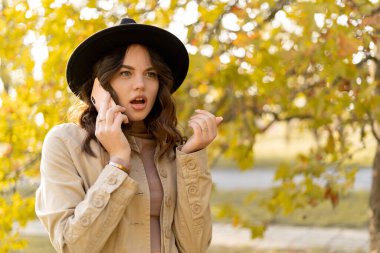 İnsan hayal kırıklığı ve üzüntü kavramı. Güz parkında cep telefonundan arayan üzgün, güzel bir kadın. Dışarıda telefonu tutan endişeli yüz ifadesi olan genç bir kız. Boşluğu kopyala