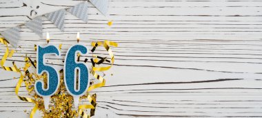 Beyaz ahşap arka planda 56 numaralı mavi kutlama mumu. 56 yaşındaki çocuğun doğum günü kutlu olsun. Uzayı kopyala Pankart.