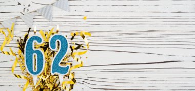 Beyaz ahşap arka planda 62 numaralı mavi kutlama mumu. Mutlu doğum günü mumları. Doğum günü, yıldönümü, önemli tarih, tatil kavramı. Uzayı kopyala Pankart