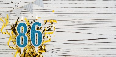 86 numaralı mavi kutlama mumu beyaz ahşap arka planda. Mutlu doğum günü mumları. Doğum günü, yıldönümü, önemli tarih, tatil kavramı. Uzayı kopyala Pankart