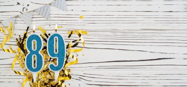 89 numaralı mavi kutlama mumu beyaz ahşap arka planda. Mutlu doğum günü mumları. Doğum günü, yıldönümü, önemli tarih, tatil kavramı. Uzayı kopyala Pankart