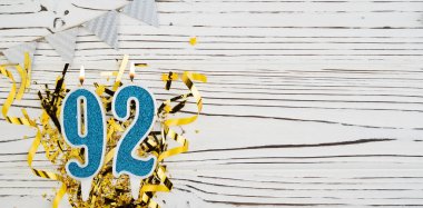 92 numaralı mavi kutlama mumu beyaz ahşap arka planda. Doksan iki yaşın kutlu olsun. Uzayı kopyala Pankart.