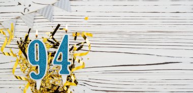 94 numaralı mavi kutlama mumu beyaz ahşap arka planda. Doksan dört yaşın kutlu olsun. Uzayı kopyala Pankart.