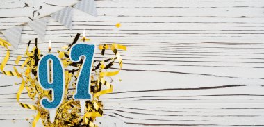 Beyaz ahşap arka planda 97 numaralı mavi kutlama mumu. Mutlu doğum günü mumları. Doğum günü, yıldönümü, önemli tarih, tatil kavramı. Uzayı kopyala Pankart