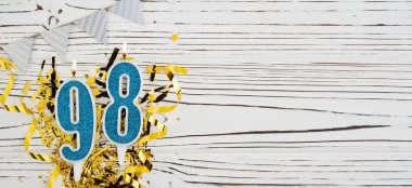 Beyaz ahşap arka planda 98 numaralı mavi kutlama mumu. Mutlu doğum günü mumları. Doğum günü, yıldönümü, önemli tarih, tatil kavramı. Uzayı kopyala Pankart