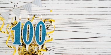 Mavi mum numarası, 100 haneli. Doğum günü tebrik kartında 100 yazılıydı. Yıldönümü konsepti. Üst Manzara. Beyaz ahşap arka planda rakam. Sayısal rakam, kutlama etkinliği. Boşluğu kopyala