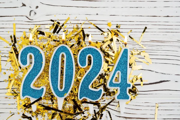 Holiday background Happy New Year 2024. Numbers of year 2024 made by blue candles on festive white wooden background. Celebrating New Year holiday concept. Copy space