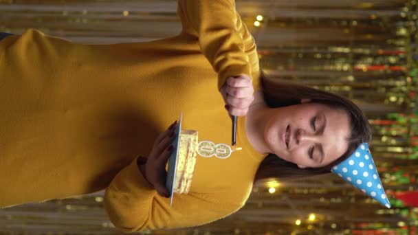 誕生日ケーキ照明ろうそくの番号8に喜びの若い女性は 黄金の背景の上に立って ホームパーティーでカメラを見て Pov 垂直ビデオ — ストック動画
