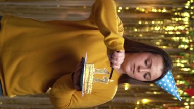 Doğum günü pastasında 17 numaralı mumları çakmakla yakan kadın. Gülümseyen kız doğum günü pastası tutuyor ve partide kameraya bakıyor. Bakış açısı. Dikey video