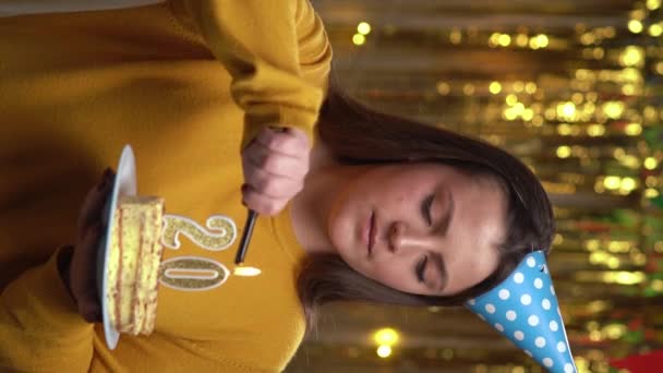 女性の照明番号20ライターで誕生日ケーキのキャンドル 誕生日ケーキを持っている笑顔の女の子とパーティーでカメラを見て Pov 垂直ビデオ — ストック動画